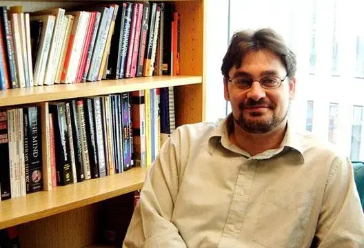 Mark Griffiths, autor y profesor, sentado junto a una estantería con libros en una oficina académica